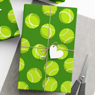 Wrapped gifts with tennis ball pattern and heart tag on green wrapping, scissors