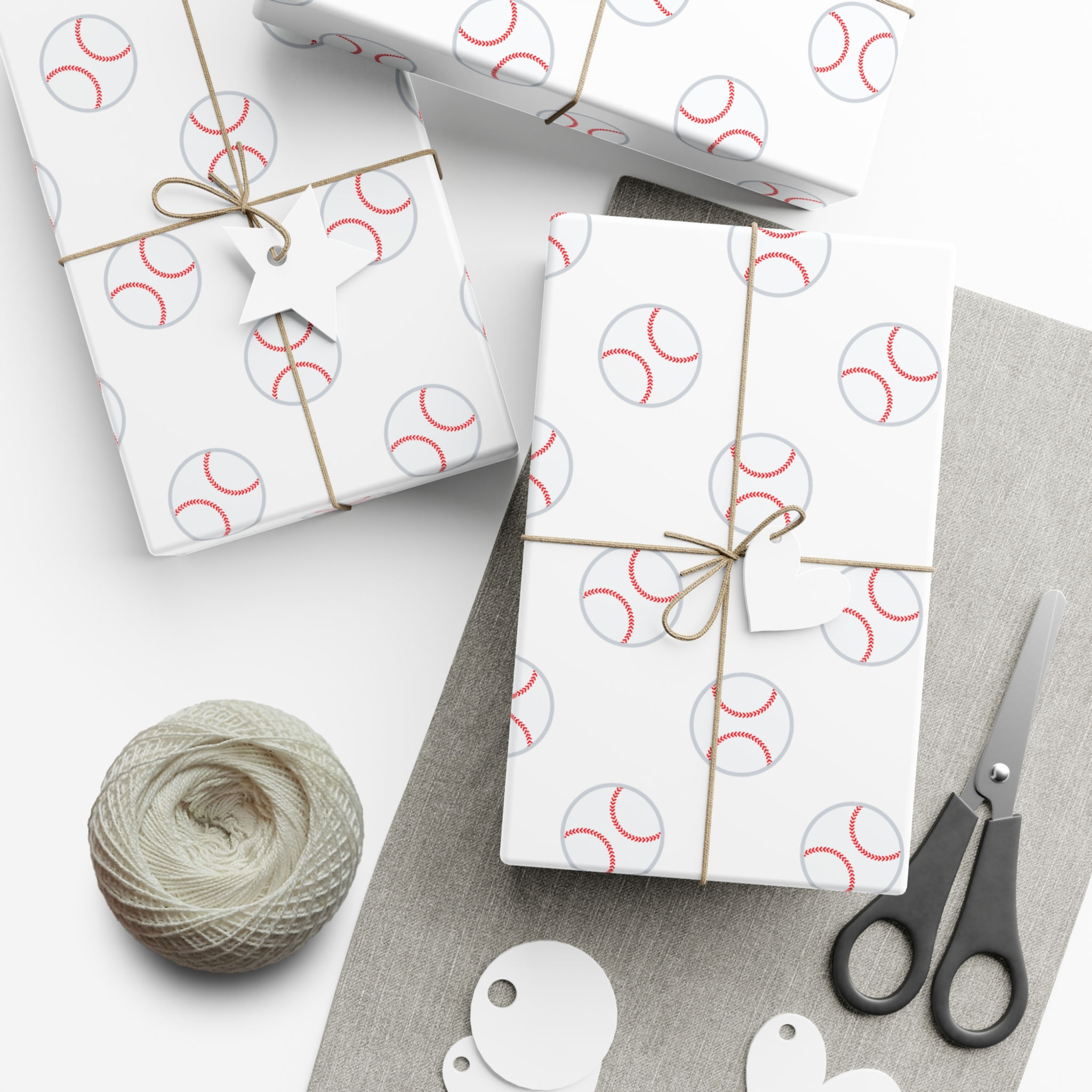 Wrapped gifts with baseball pattern, twine, scissors, and blank tags on table.