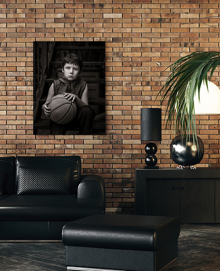 Black & white image of child holding basketball displayed on brick wall