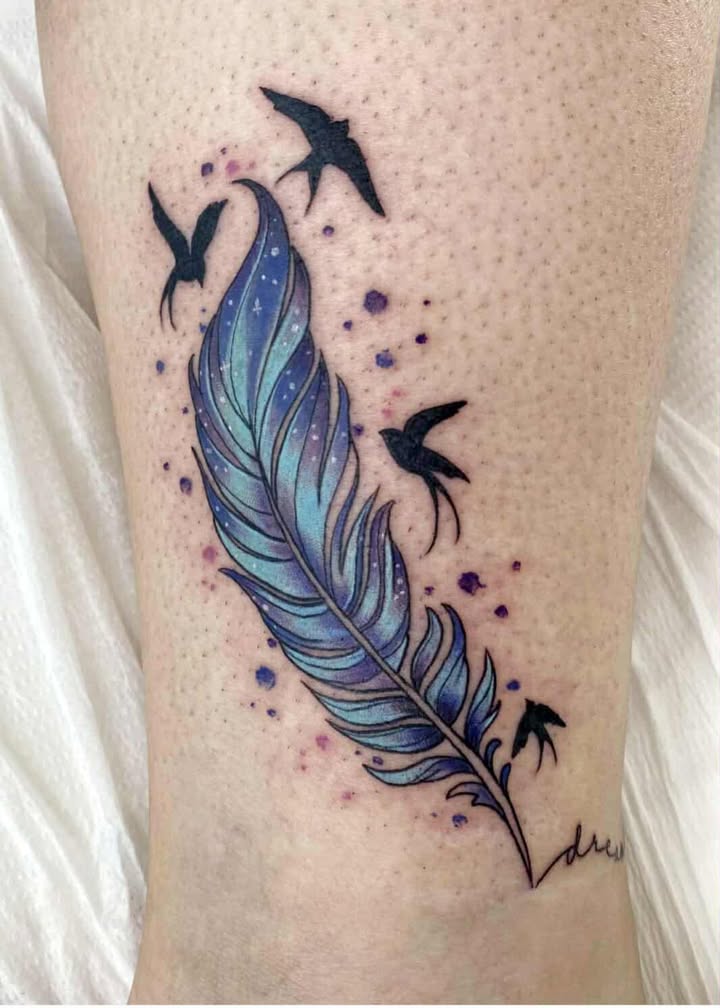 Blue and purple feather tattoo dissolving into flying birds, with scattered dots, on an upper arm