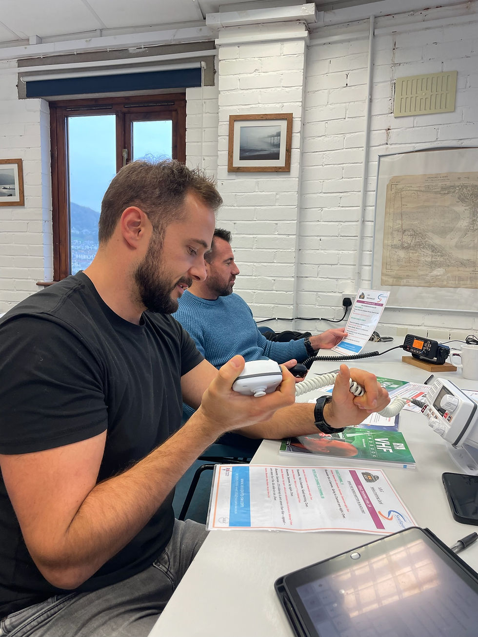 Two team members learning VHF radio communication during the SRC Marine Radio course led by Tim Cox at SeaSports Southwest