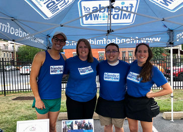 Smiling group of board members under a Friends of Midtown tent