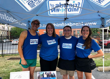 Smiling group of board members under a Friends of Midtown tent