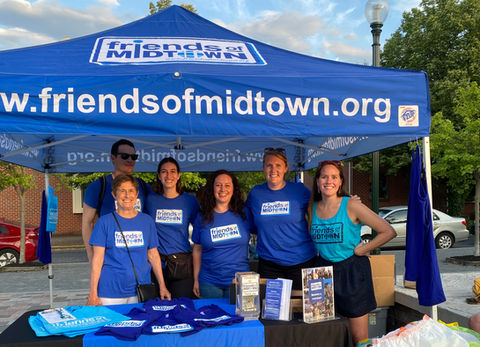 Smiling group of board members under a Friends of Midtown tent