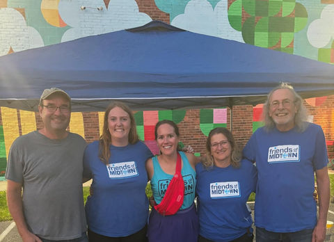Smiling group of board members in front of a Friends of Midtown tent