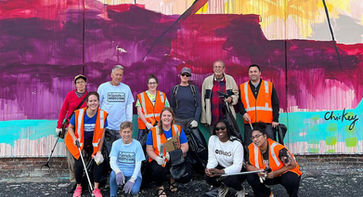 Group posing in front of a mural after a trash cleanup
