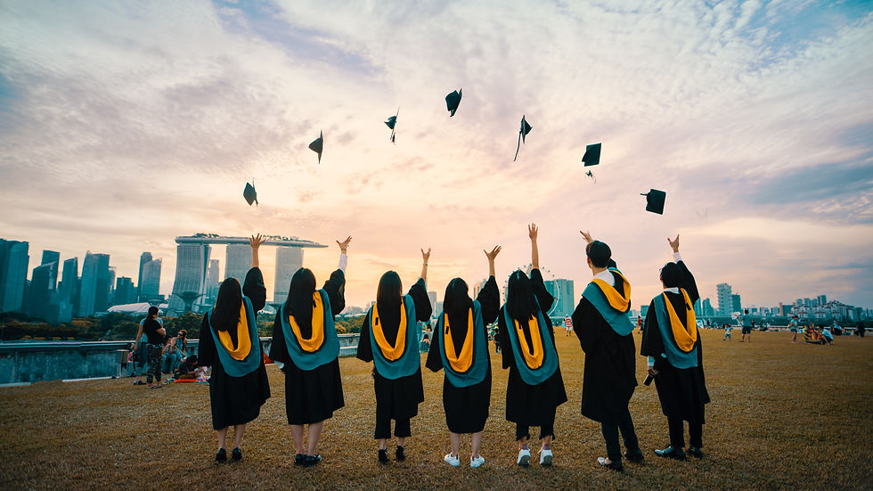 Graduates in caps and gowns toss hats in celebration against a city skyline at sunset, creating a joyful atmosphere.