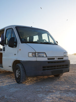White campervan parked by the ocean at sunset