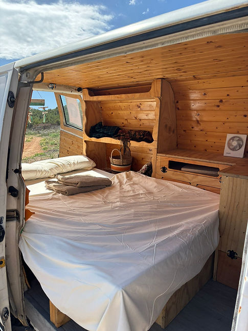Cozy campervan interior: bed, shelves, wooden paneling