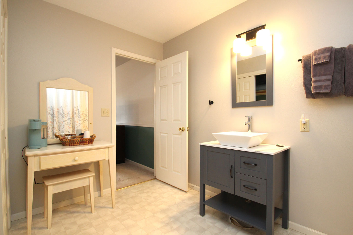 Bathroom with sink, mirror, and open door, providing a view to other room.