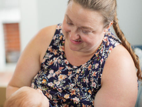 A Jacksonville overnight newborn care specialist holds a newborn in her arms and smiles down as she looks at him