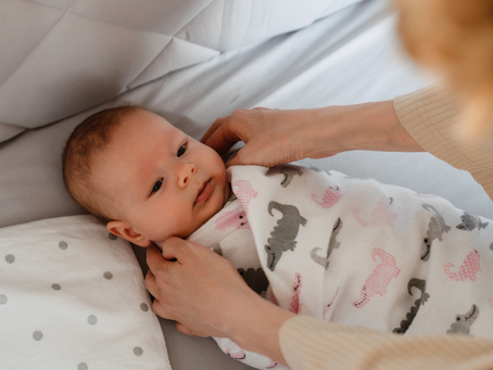 A new mom learning how to swaddle a newborn with The Jacksonville Baby Company by her side.