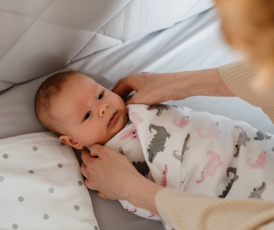A new mom learning how to swaddle a newborn with The Jacksonville Baby Company by her side.