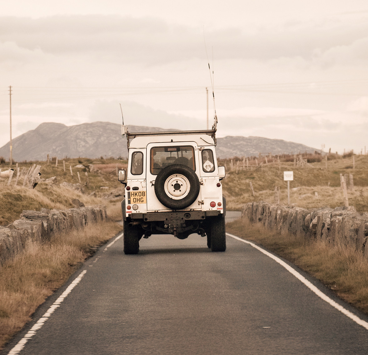 A white Land Rover Defender driving in N