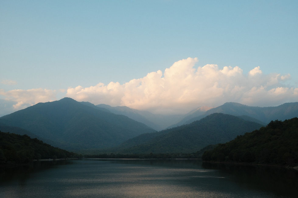 Calm lake with mountains and clouds in the background.