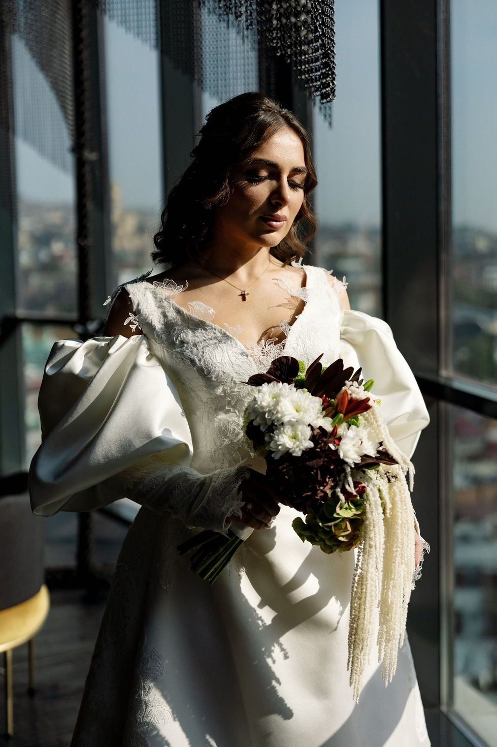 Bride holding bouquet in sunlit room.