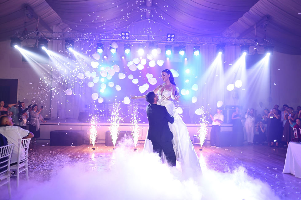 Bride and groom dancing amid lights and smoke.