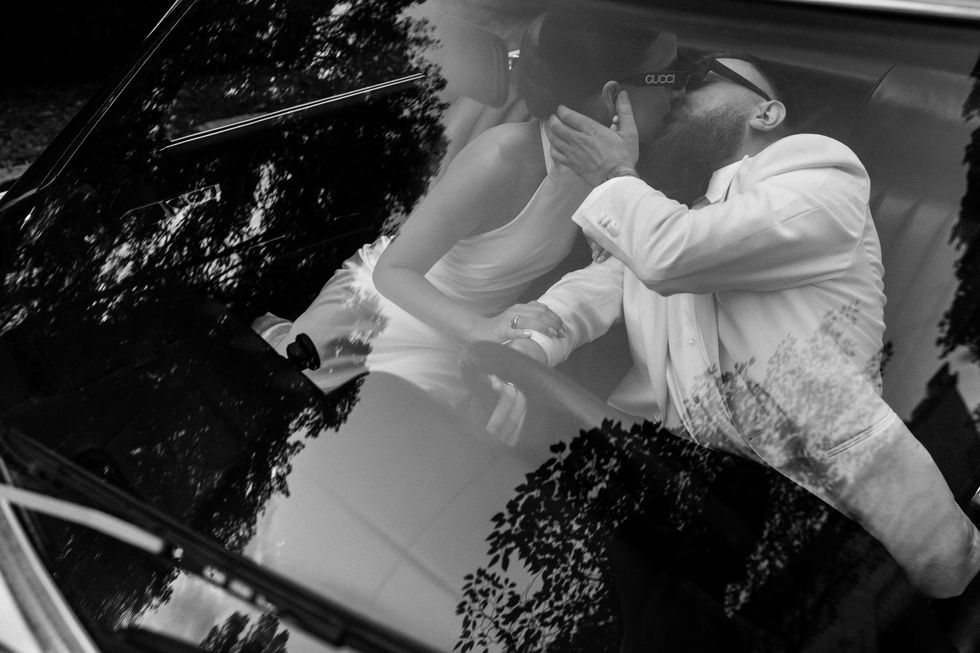 Black and white photo of couple kissing in car.
