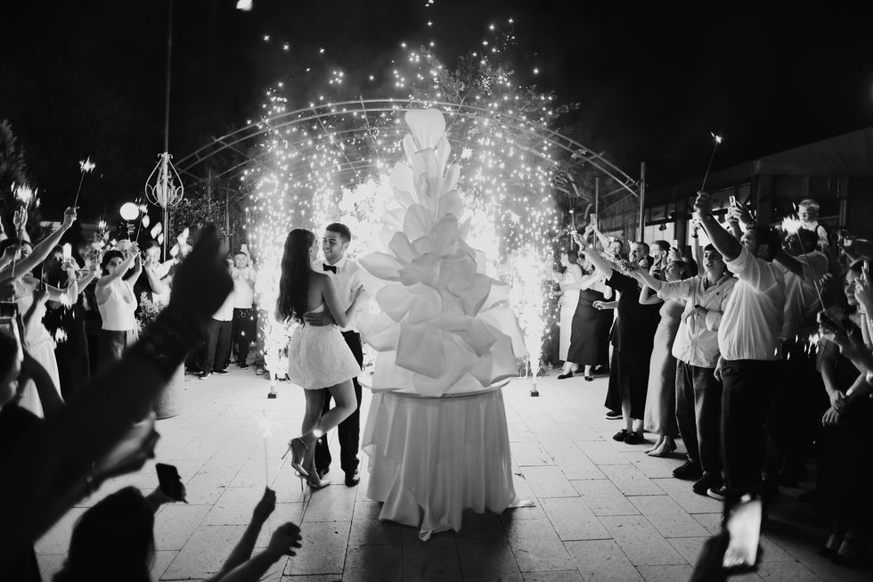 Couple dancing near large cake with sparklers.