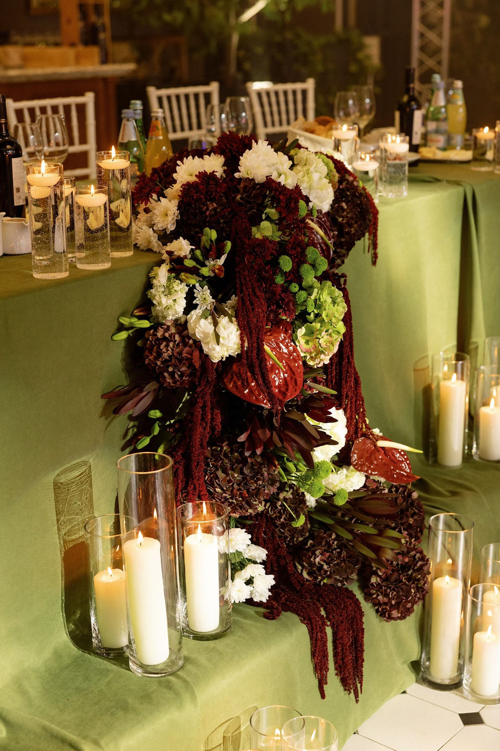Elegant floral arrangement with candles on a green table.