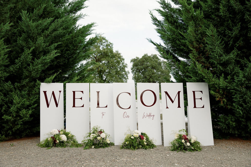 Large "Welcome" sign with greenery and flowers.