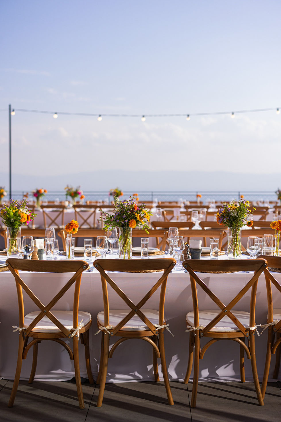 Outdoor dining setup with flowers and string lights.