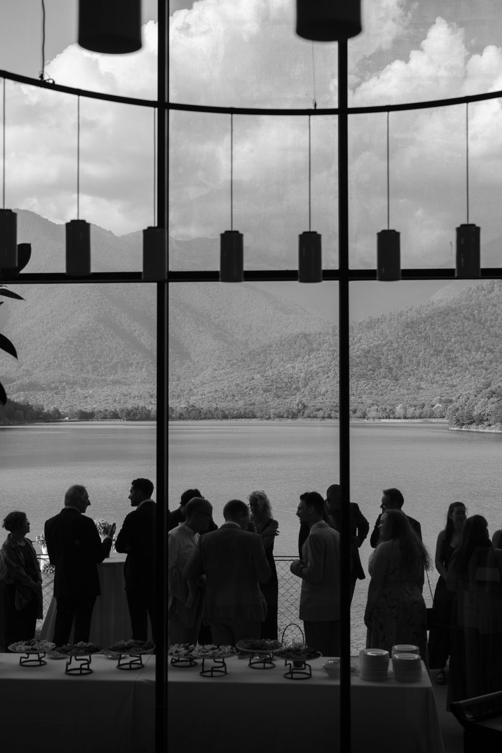 Silhouetted people in front of large window, mountain view.
