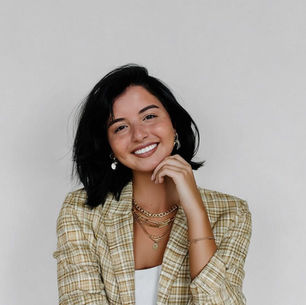 woman with short black hair, gold jewelry and a yellow plaid sports jacket smiling at the camera