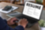 Professional business person sitting in front of a laptop updating their resume.