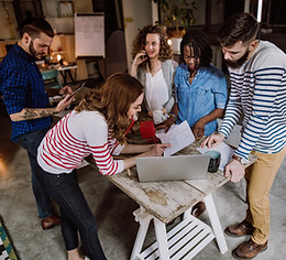 Team members discussing ideas while working together on laptops