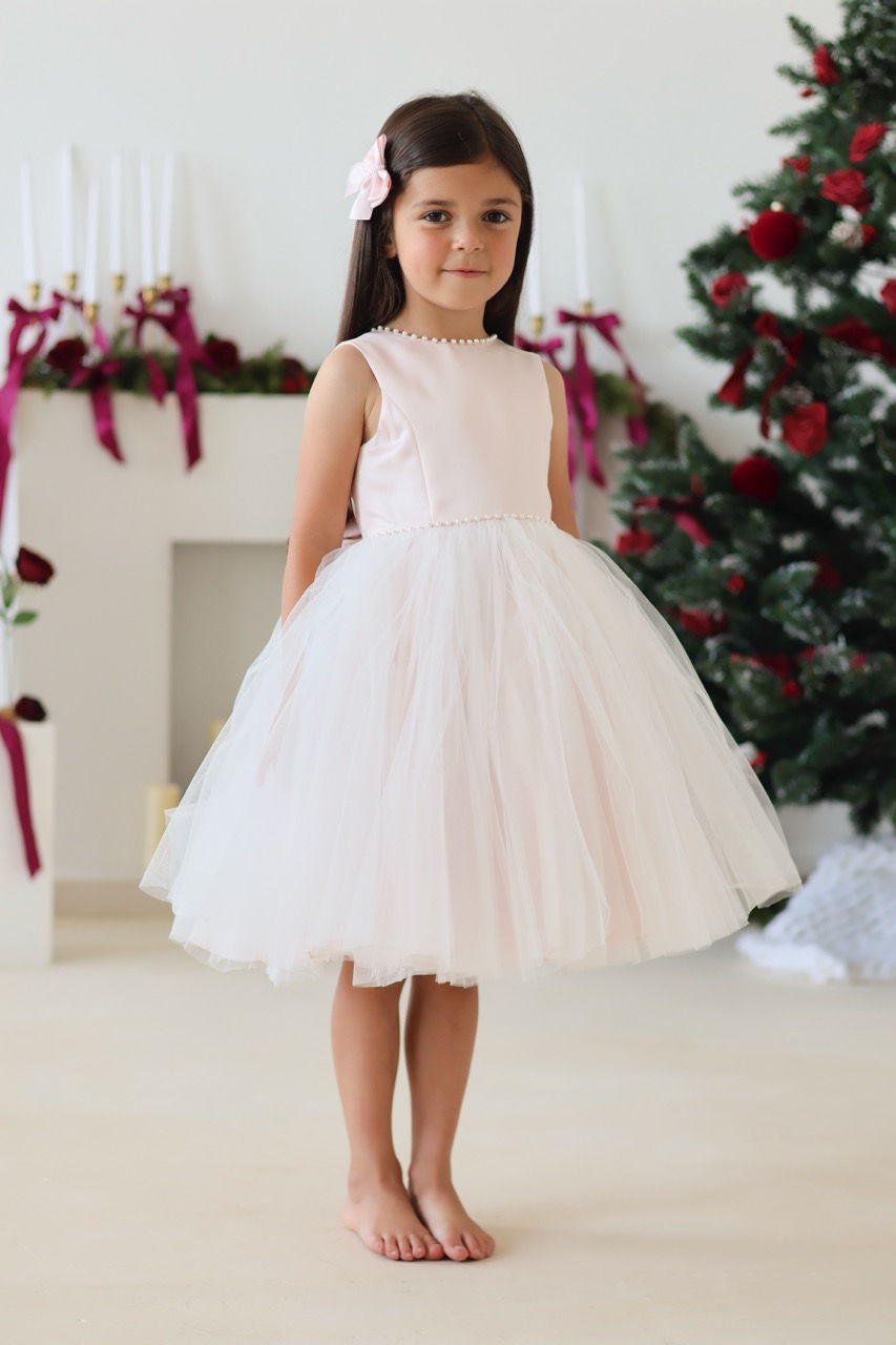 Thumbnail: Sarah Louise Ballerina Pearl Dress in a soft pastel peach, a large back bow and a full tulle skirt