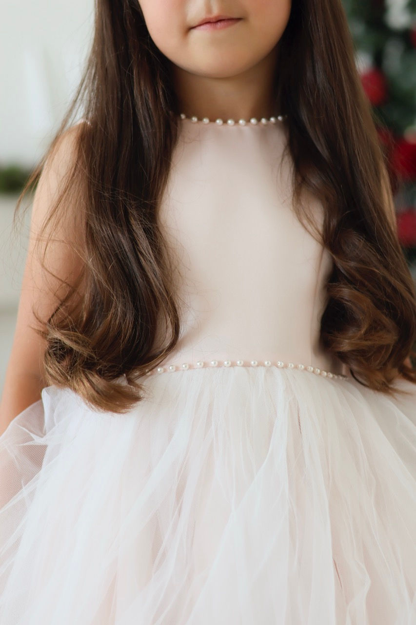 Thumbnail: Sarah Louise Ballerina Pearl Dress in a soft pastel peach, a large back bow and a full tulle skirt