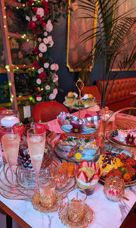 Elegant dessert table with champagne, parfaits, tiered sweets, and rose garlands.