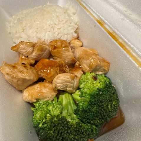 Chicken and broccoli meal with rice in a white takeout container.