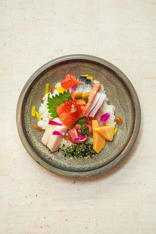 Overhead view of a colorful chirashi bowl Yoi Sushi with various seafood, rice.