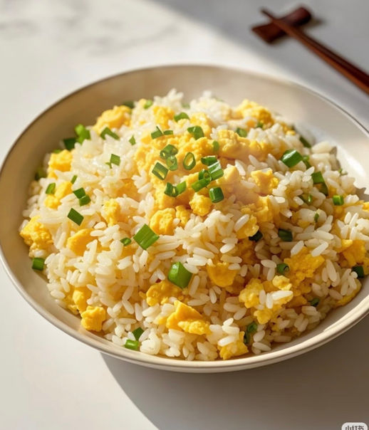 一碗美味的炒饭，配有鸡蛋和葱，旁边有筷子，食物。