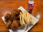 炸鸡腿、薯条和可乐。Chicken's Corner在木桌上摆放着美味的食物。