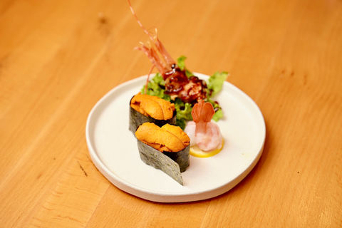 Two sea urchin sushi on a plate with shrimp and Yoi Sushi.