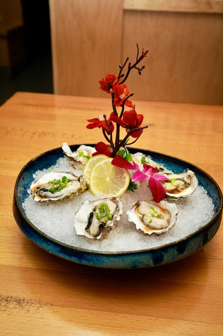 Fresh oysters on ice with lemon and floral decoration at Yoi Sushi