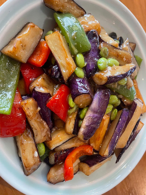 Colorful stir-fried eggplant, bell peppers, and edamame in a glossy sauce.