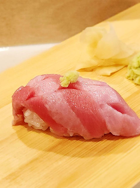 Fresh tuna nigiri sushi on wooden board with wasabi and ginger