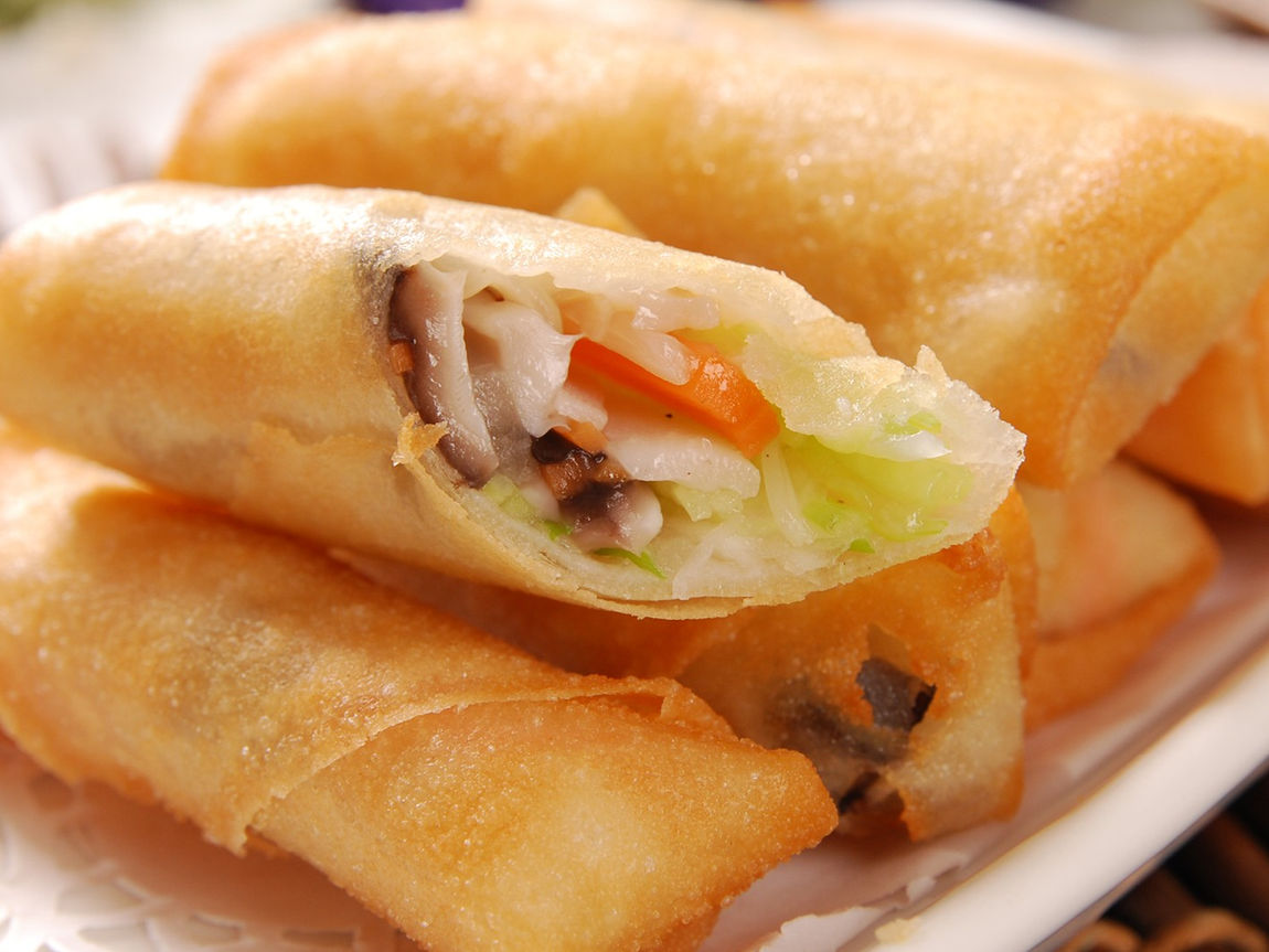 Close-up of golden spring rolls showing the fresh vegetable filling