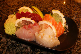 盘子里的新鲜生鱼片,配有柠檬和姜,美味可口,准备享用。