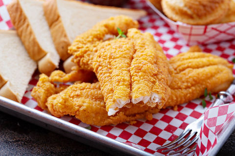 Golden fried fish fillets with bread on a checkered tray