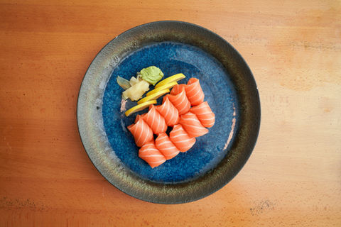 Salmon sushi rolls on a blue plate with wasabi and ginger. Yoi Sushi