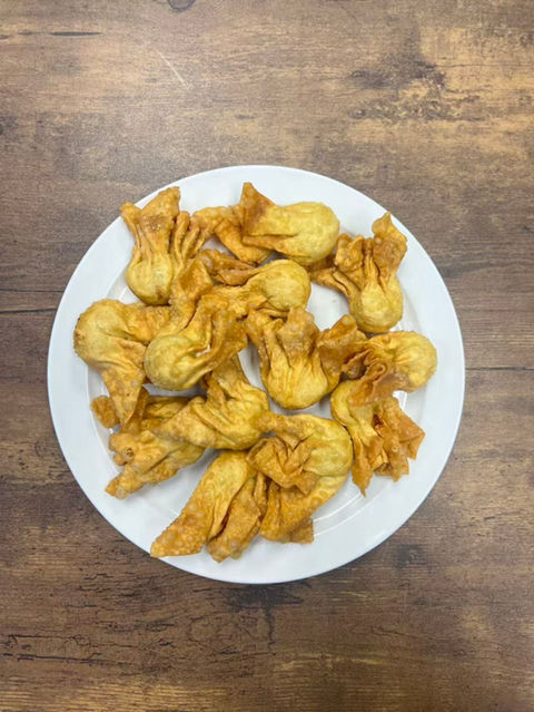 Plate of fried wontons, a delicious appetizer on a wooden table.