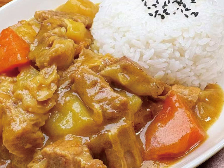 Delicious Japanese curry with rice, potatoes, carrots, and meat, close-up shot.