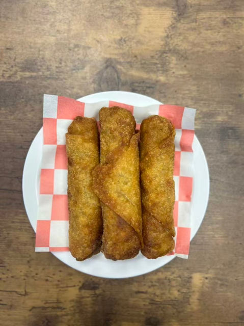 Three golden egg rolls on a plate with red checkered paper HOME