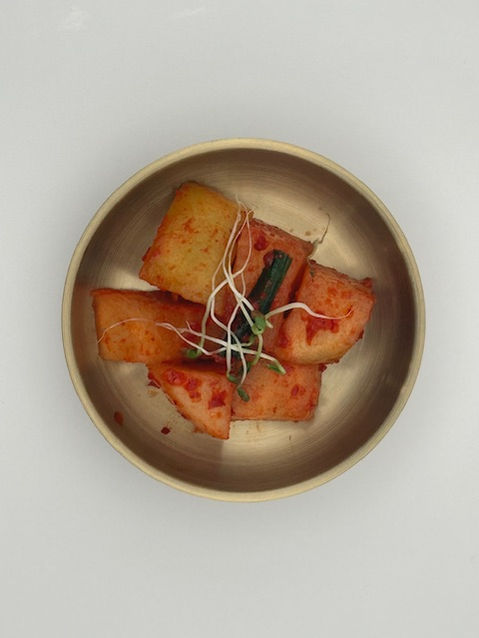 Diced radish kimchi with sprouts in a metal bowl