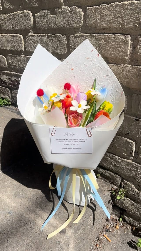 Bouquet of colorful flowers with white paper and ribbons
